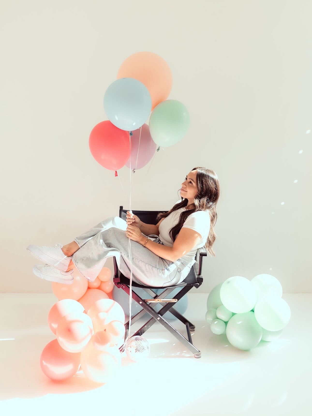 Founder of AZ Party Co. relaxing in a director chair holding pastel balloons