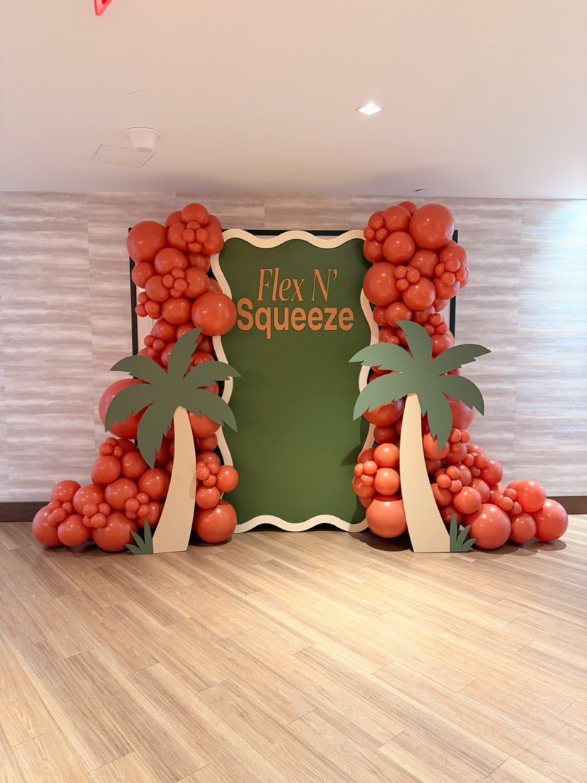 Flex N Squeeze corporate balloon activation with palm trees and green backdrop by AZ Party Co.